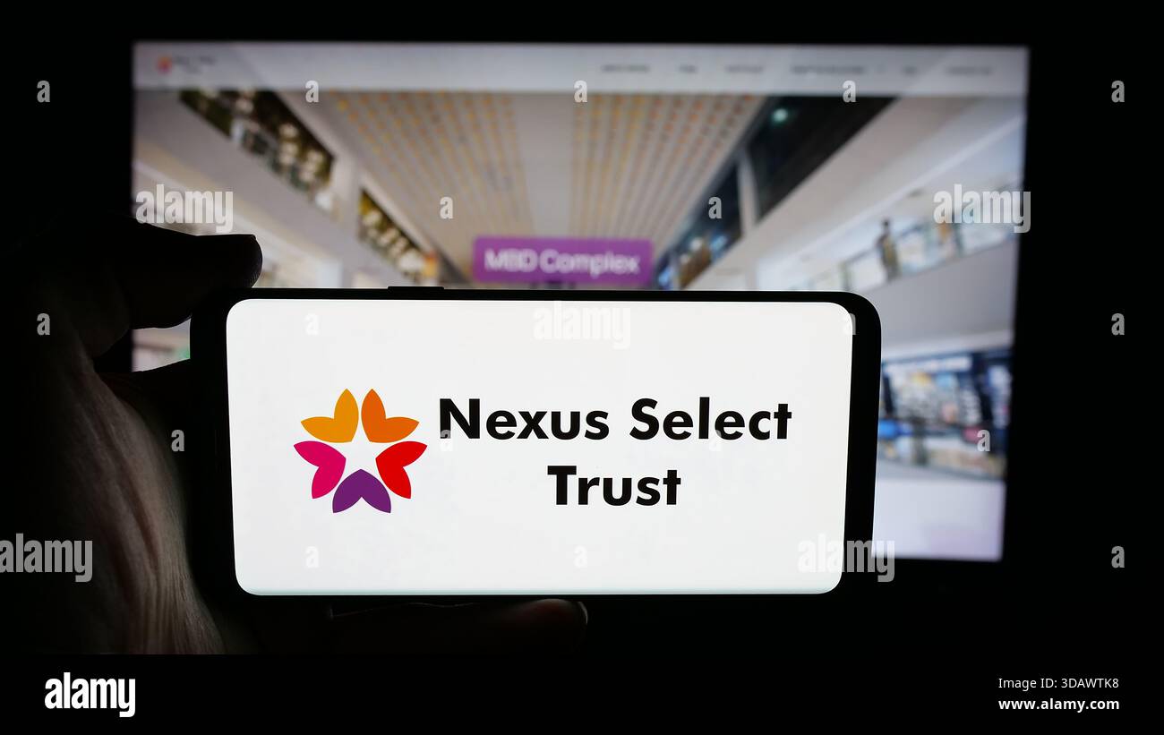 Stuttgart, Germany - 11-30-2025: Person holding cellphone with logo of Indian real estate company Nexus Select Trust on screen in front of webpage. Stock Photo