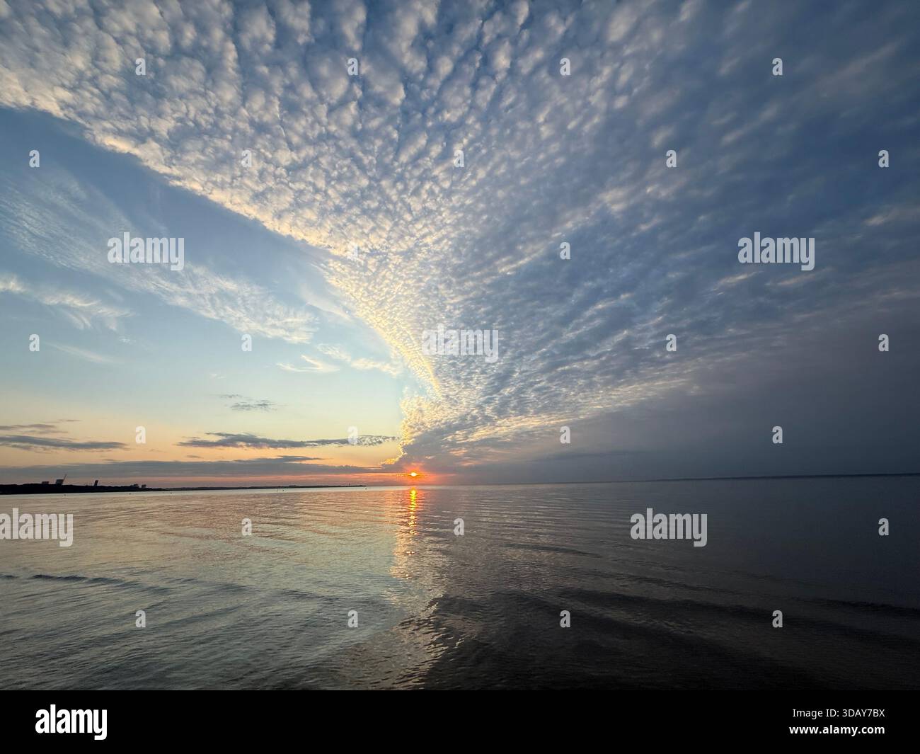A glowing red sun rises over the Baltic Sea and is reflected in the waters of Lübeck Bay. Eine glutrote Sonne geht über der Ostsee auf. - Smartphone Captured Stock Image