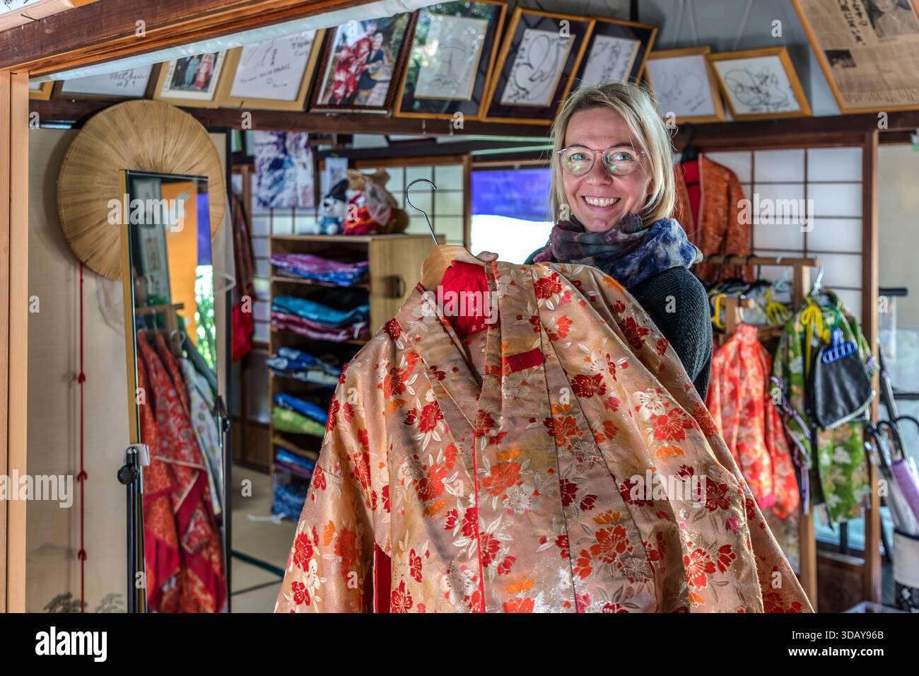 For the kimono experience on the Kumano Kodo pilgrimage route, visitors choose their favourite kimono from many different patterns and colours. A tourist has picked out a rental kimono to wear while walking part of the pilgrimage route; the kimono is fitted with professional help. Nachikatsuura, Wakayama Prefecture, Japan. Stock Photo