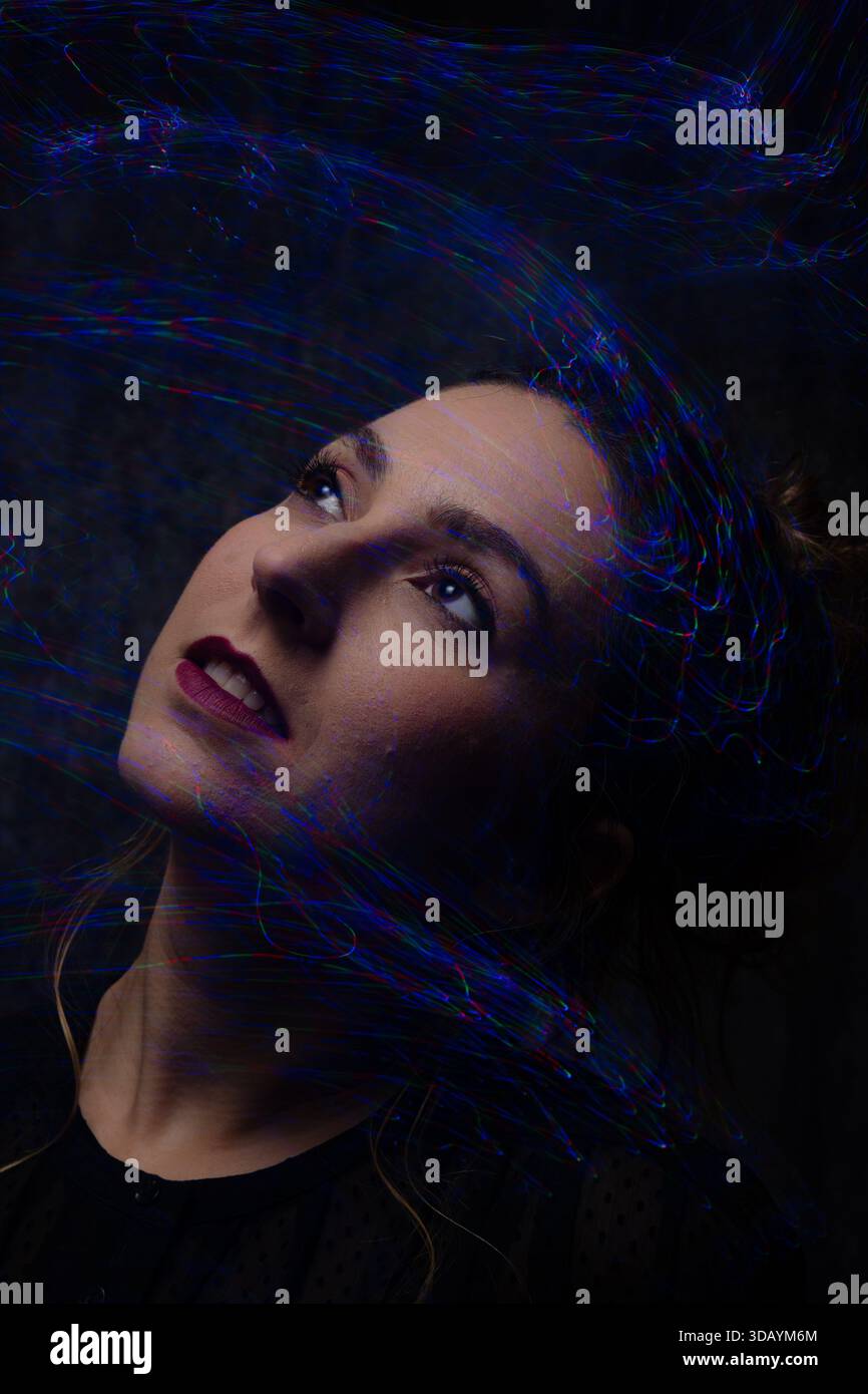 Woman light painting portrait looking up with abstract trails Stock Photo