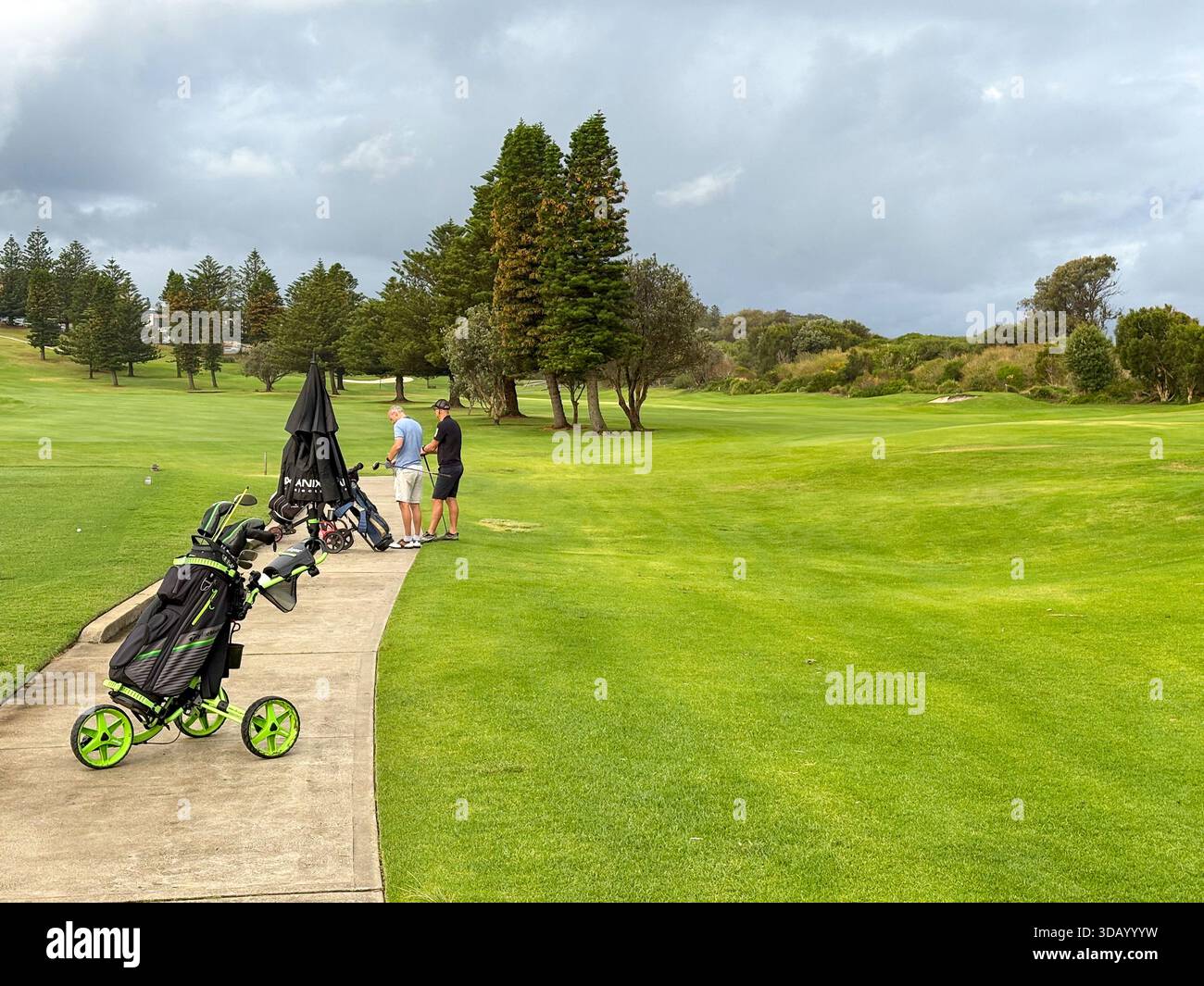 Play Golf Australia, two male golfers with their golf club bags and push buggies on Mona Vale golf course,Sydney,NSW,Australia - Smartphone Captured Stock Image