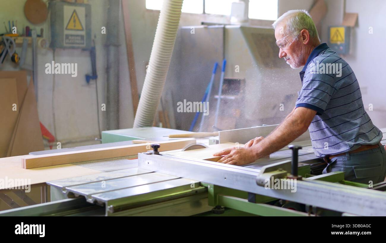 Senior carpenter working with circular saw in workshop Stock Photo