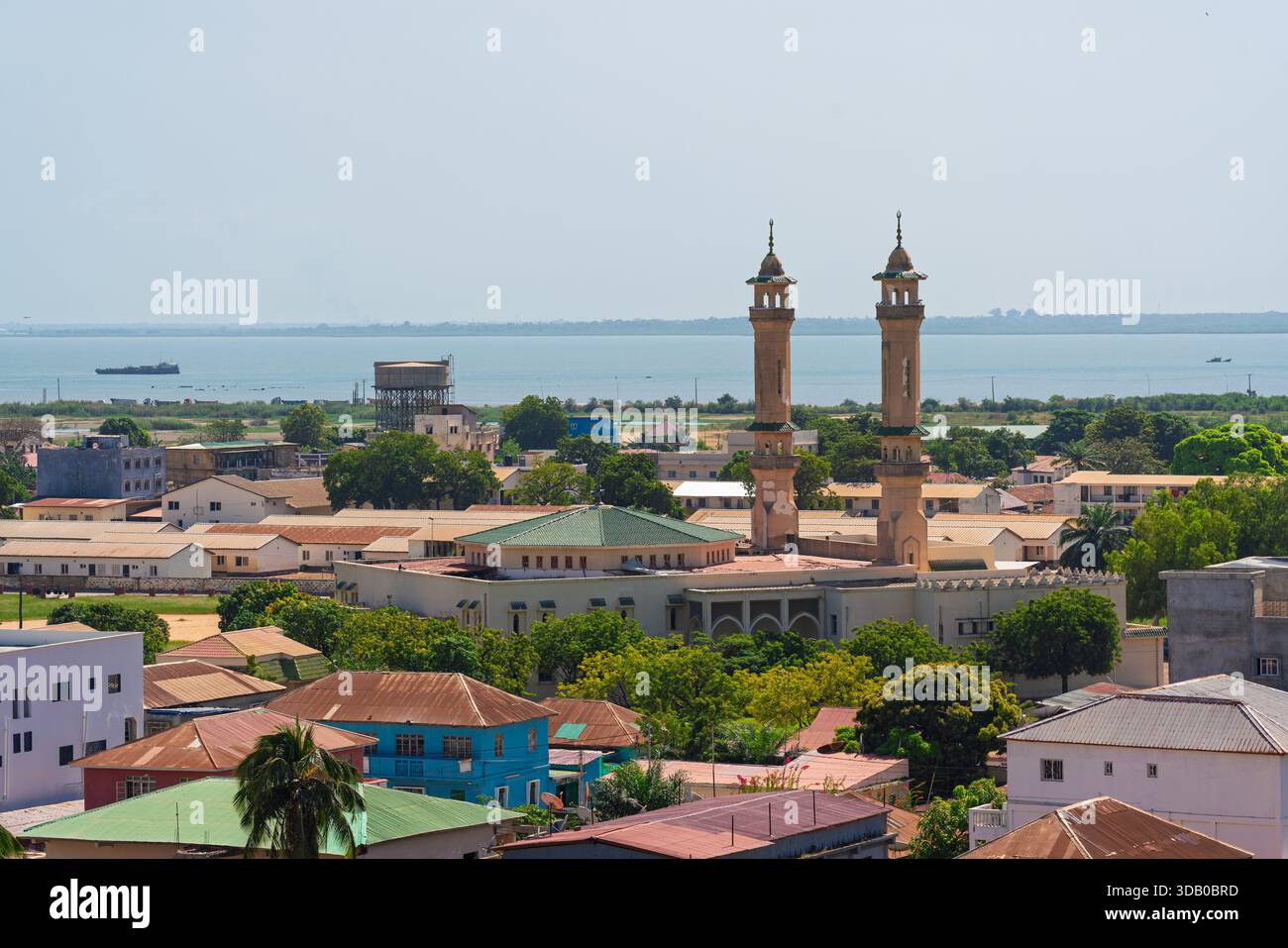 Banjul, Gambia. Elevated view of the city showing a large mosque, residential rooftops, and the distant river estuary Stock Photo