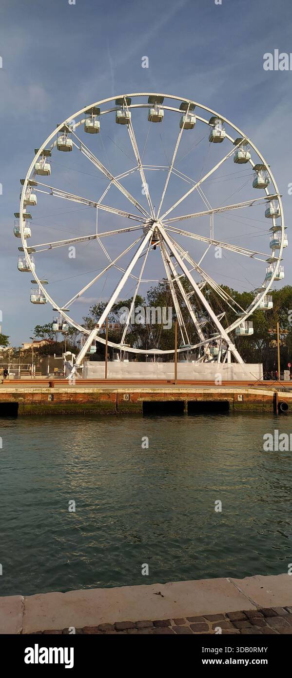 The Ferris wheel is located on the canal port and is used in the summer by tourists on holiday in Romagna. - Stock Image