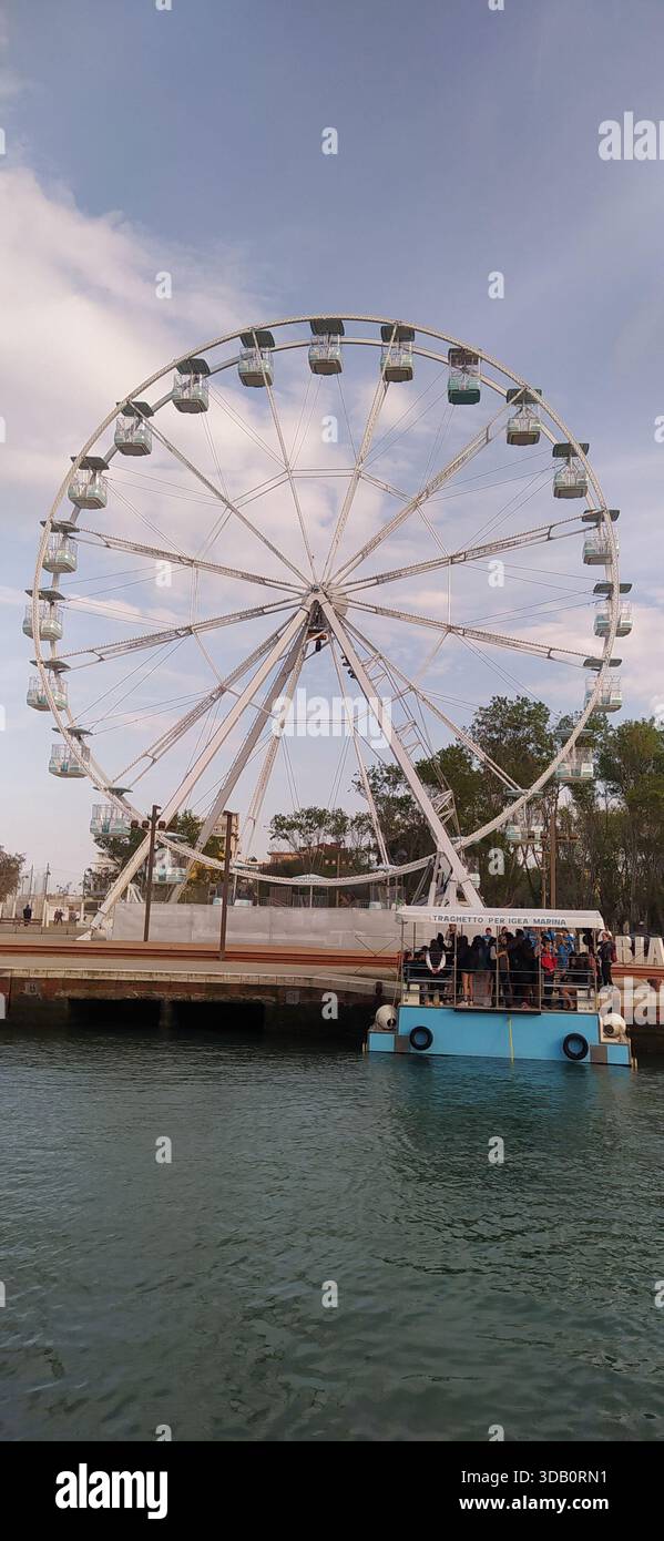 The Ferris wheel is located on the canal port and is used in the summer by tourists on holiday in Romagna. - Stock Image