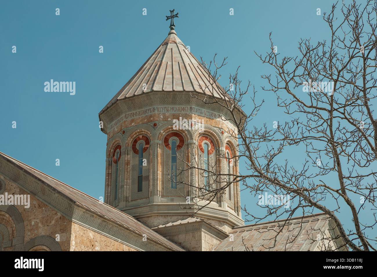 A historic stone church with a domed tower and cross stands against a ...