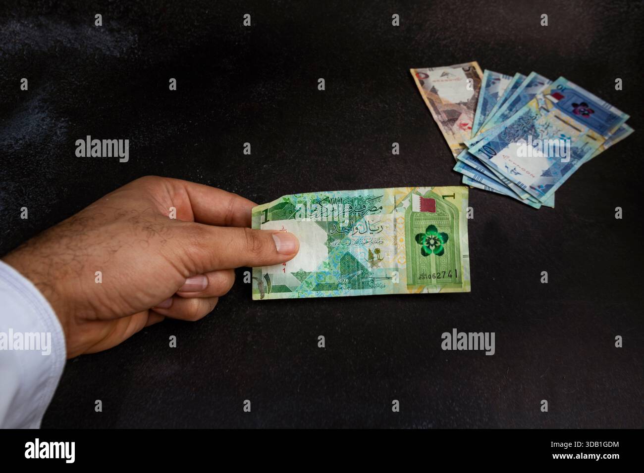 Hand holding Qatari riyal banknote, close-up of Qatar currency showing ...