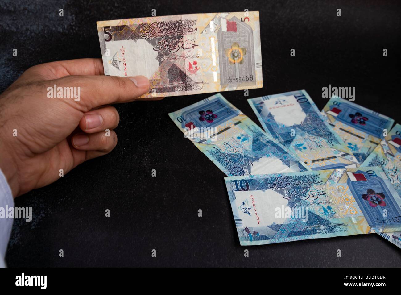 Hand holding Qatari riyal banknote, close-up of Qatar currency showing ...