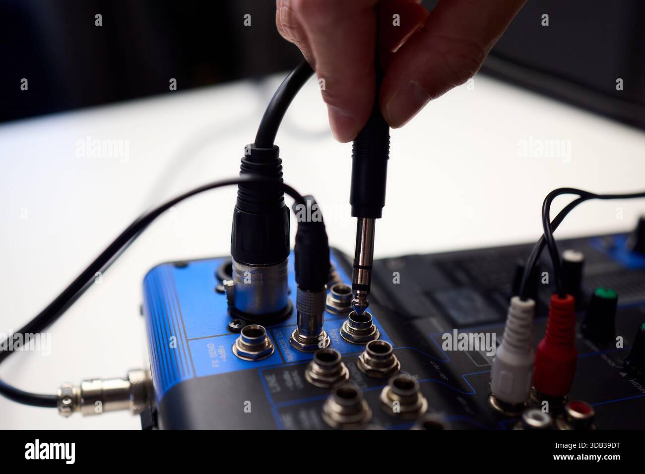 Fitting cables into professional studio gear, Attaching connectors carefully on live music setup, Ensuring accurate cable connections on audio Stock Photo