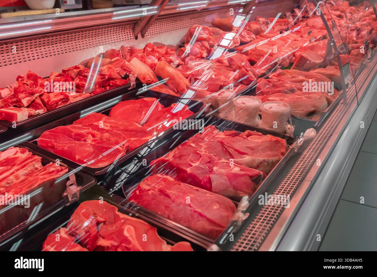 Fresh red meat display at a shop featuring beef and pork cuts in a well ...