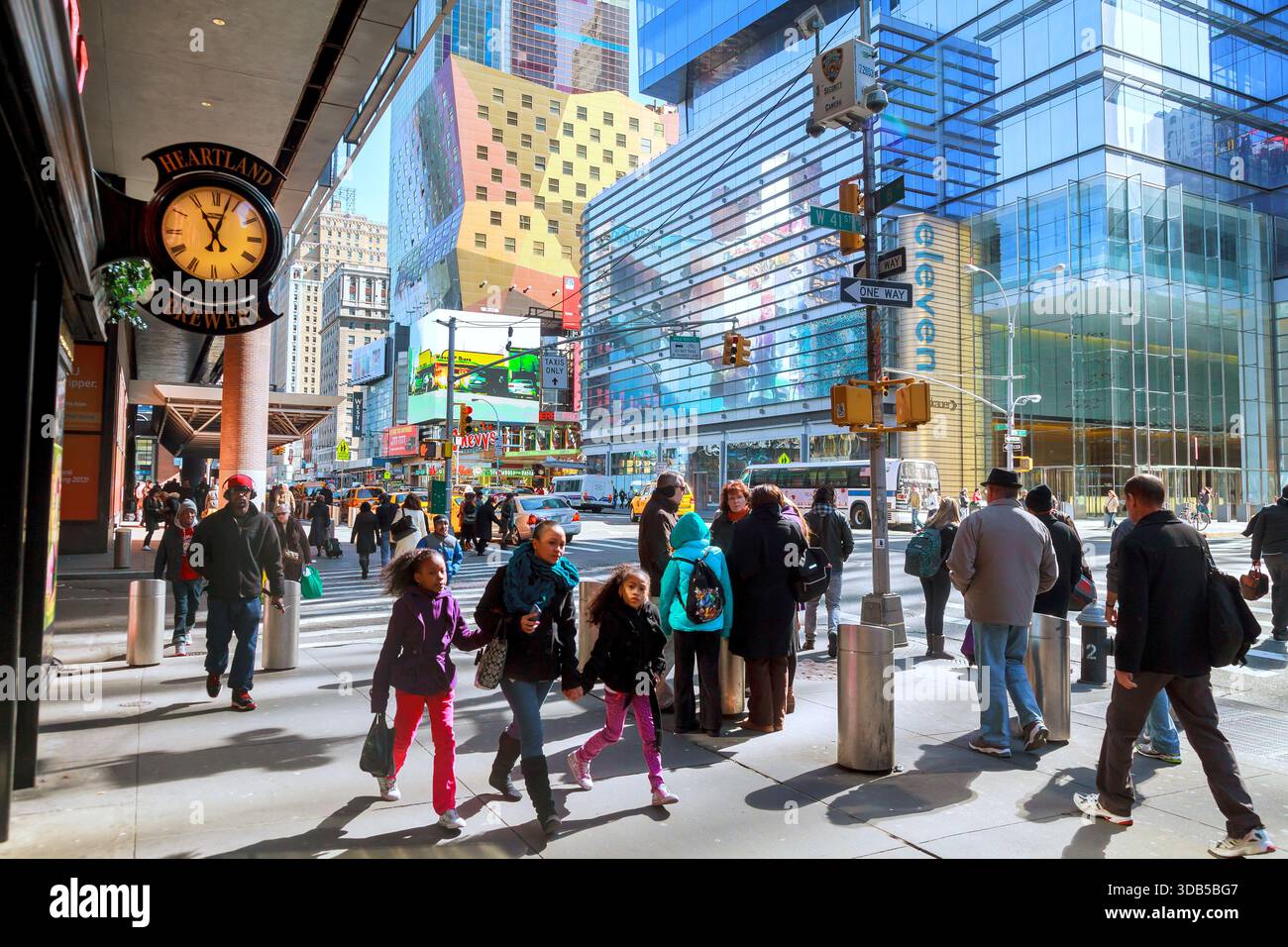 People walk on street in New York City with tall buildings bright signs ...