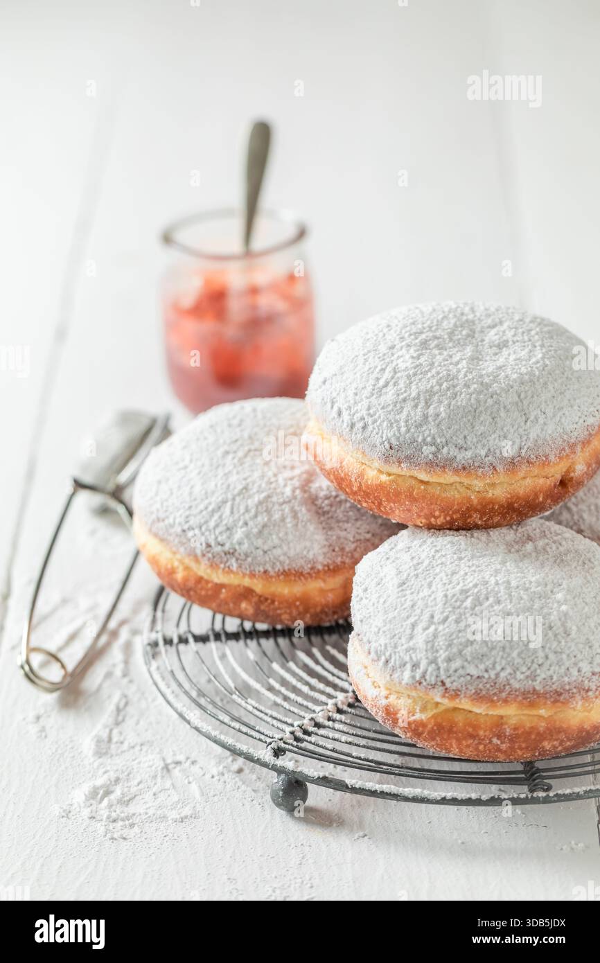 Sweet donuts with white icing on cooling grate on white table Stock Photo
