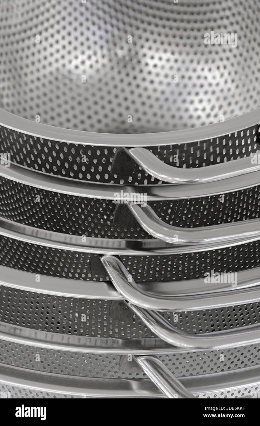 Group of round stainless steel collanders, various sizes, empty and clean, close-up shot, abstract background Stock Photo