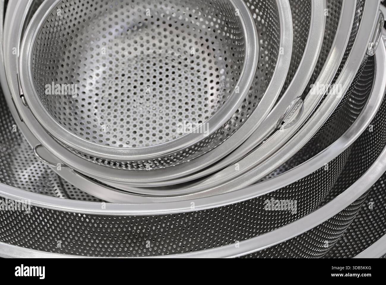 Group of round stainless steel collanders, various sizes, empty and clean, close-up shot, abstract background Stock Photo