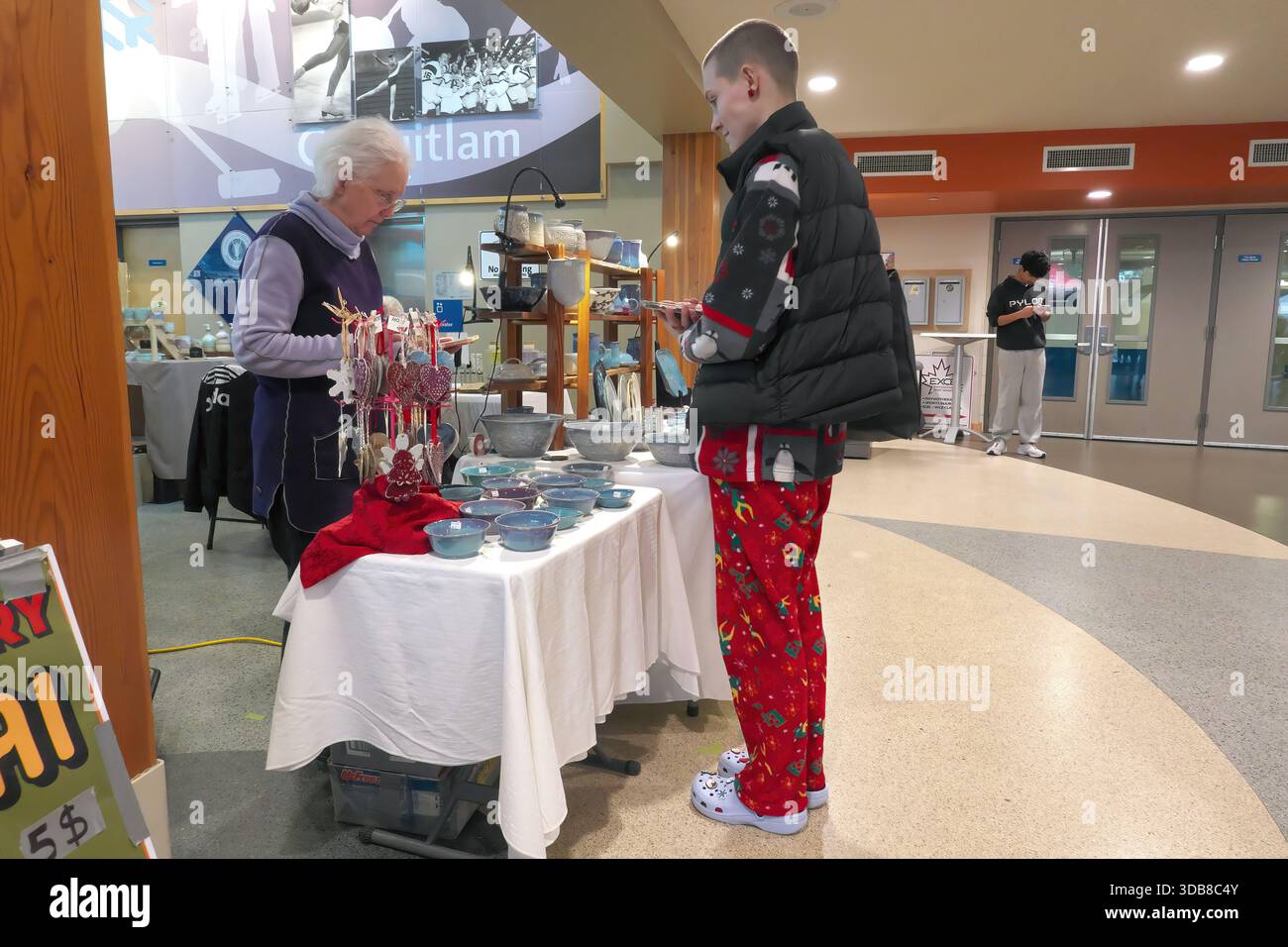 Shopper purchasing a piece of pottery at a Christmas Farmers Market, Coquitlam, B. C, Canada - December 13, 2025 Stock Photo