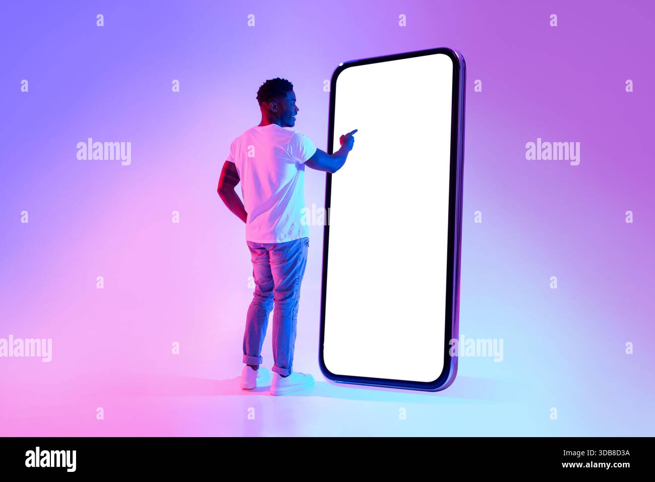 Young Black Man Interacts With Large Smartphone Screen in Neon Lighting for App Design Stock Photo