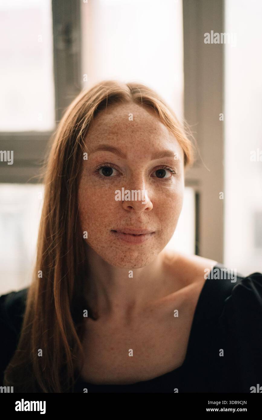A red-haired woman with freckles looks into the camera Stock Photo