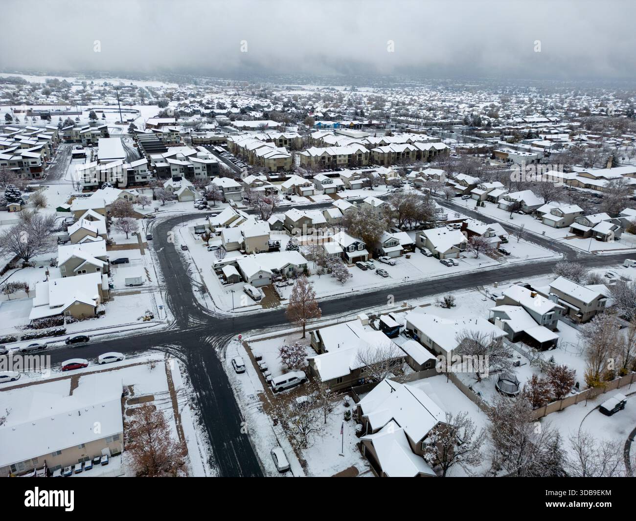 Aerial view of a snow-blanketed suburban neighborhood with houses and streets under a veil of winter's quietude, Layton, Utah, United States. Stock Photo