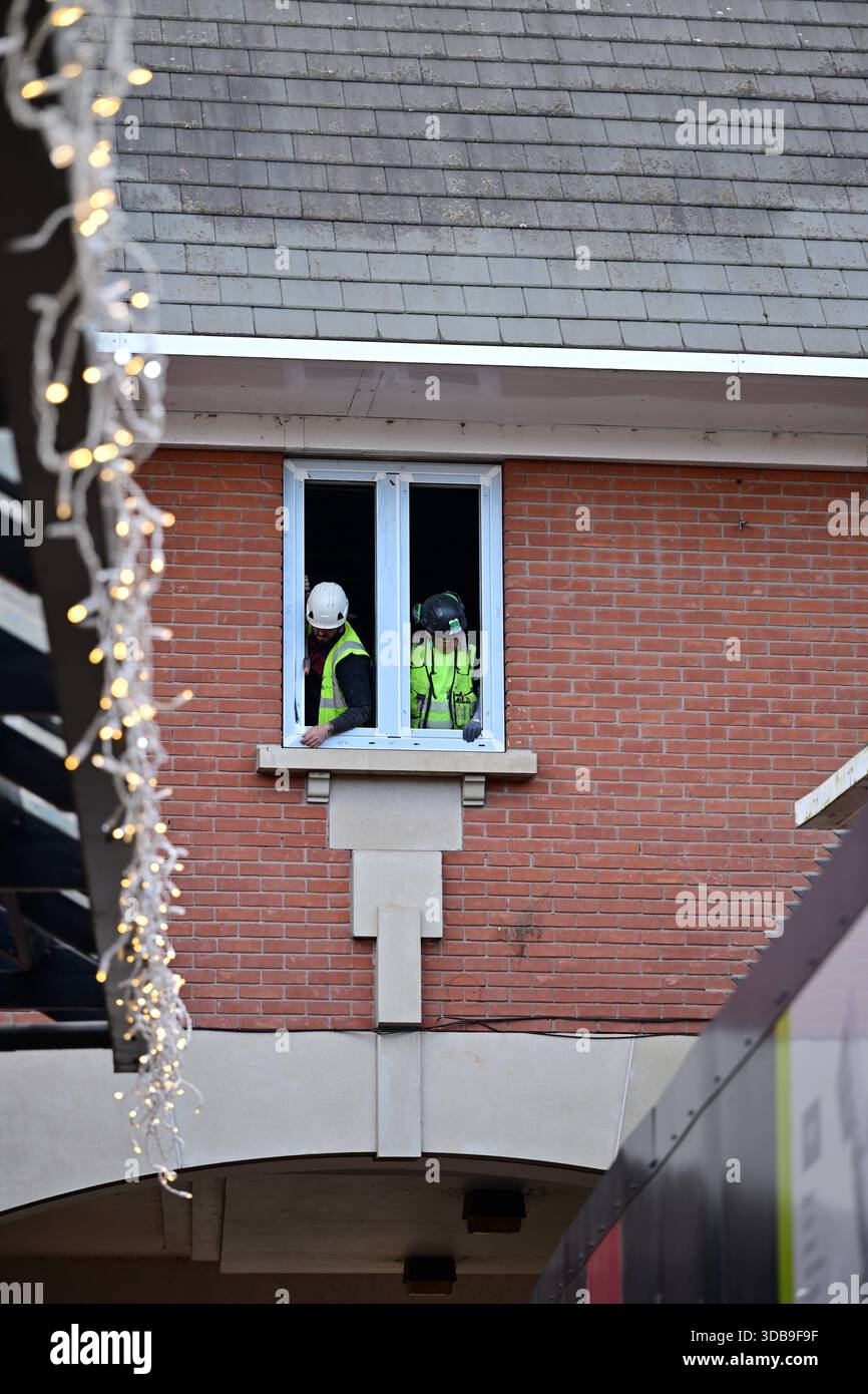 Two Construction Workers Installing a Window on Brick Building Stock Photo