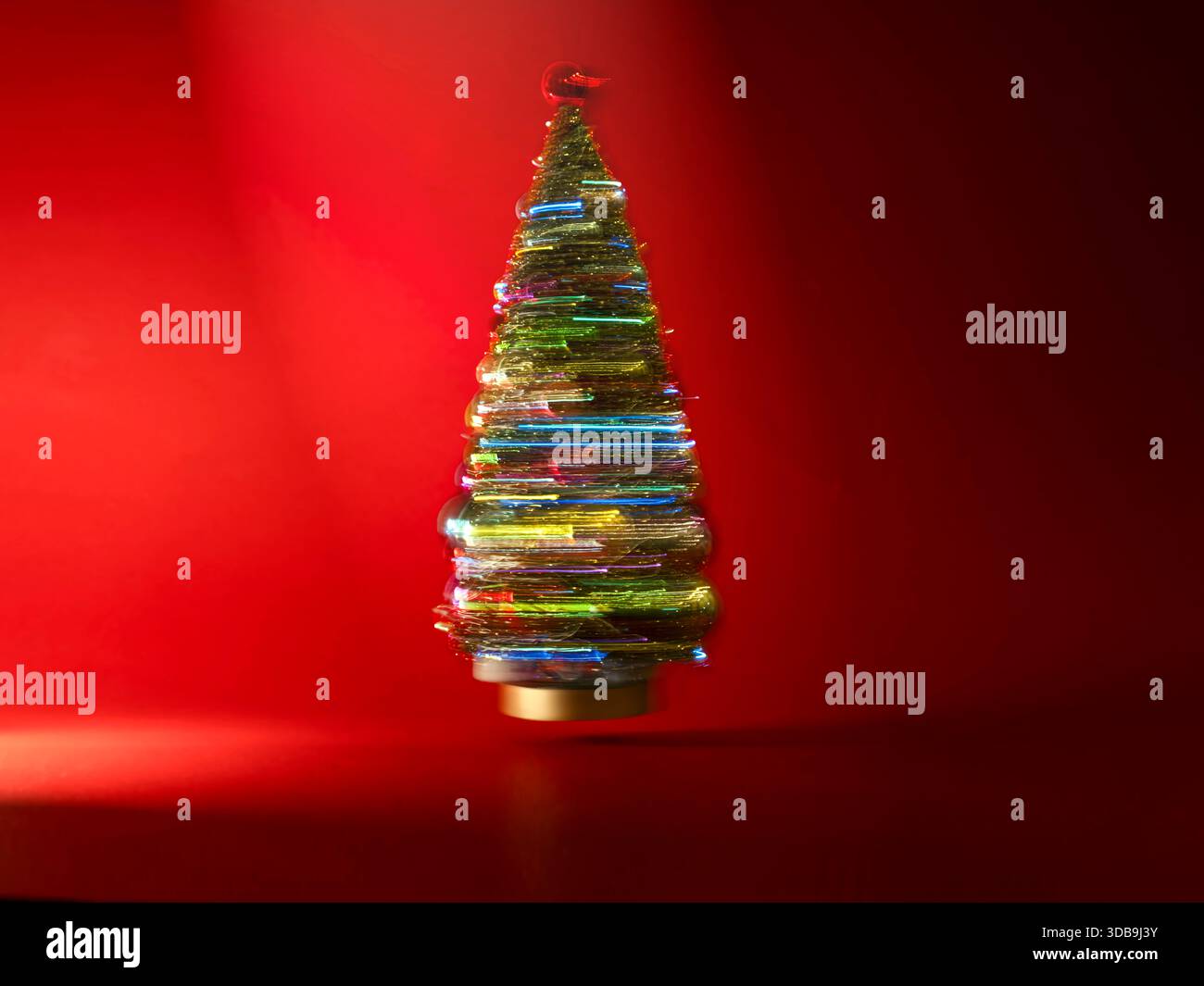 Close-up of a colourful glass Christmas tree ornament in front of a red background Stock Photo