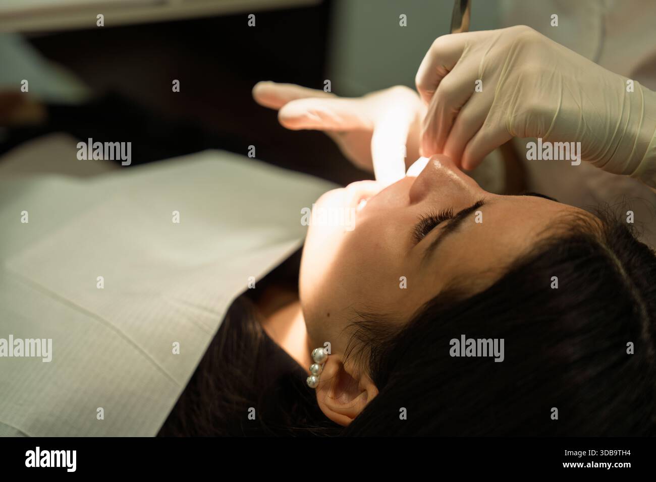 Dentist performing oral care procedure on patient in clinic Stock Photo