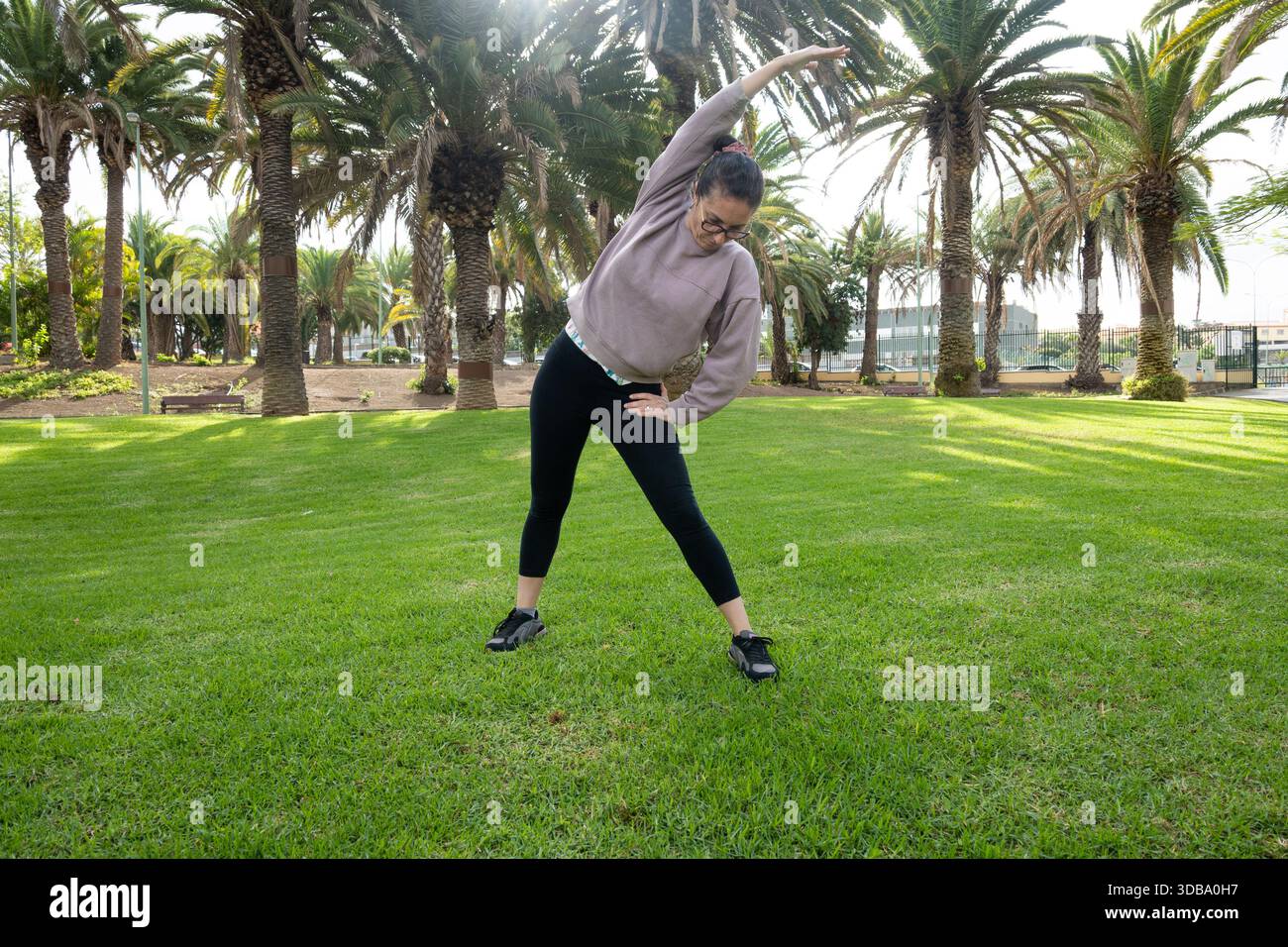 Woman doing side stretch exercise outdoors in a park Stock Photo