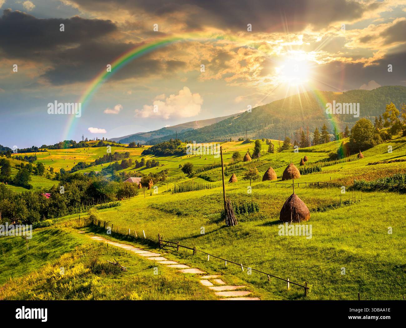 beautiful countryside scenery in summertime at sunset. haystack on grassy hillsides of mountain in evening light. rolling landscape under cloudy sky. Stock Photo