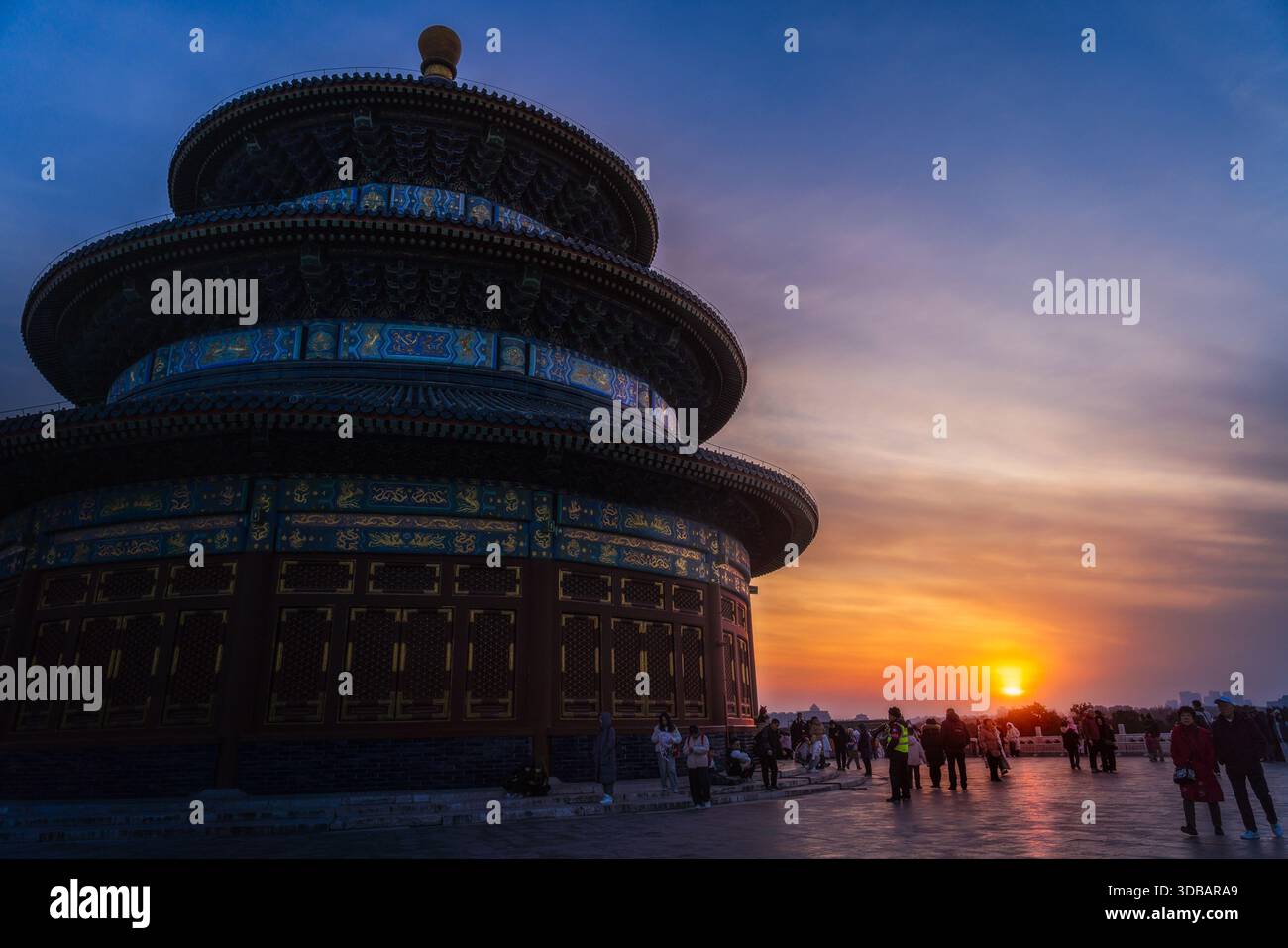 View of the Temple of Heaven's tiered structure rises majestically against a vibrant sunset, as silhouettes of people gather below, Beijing, Beijing, Stock Photo