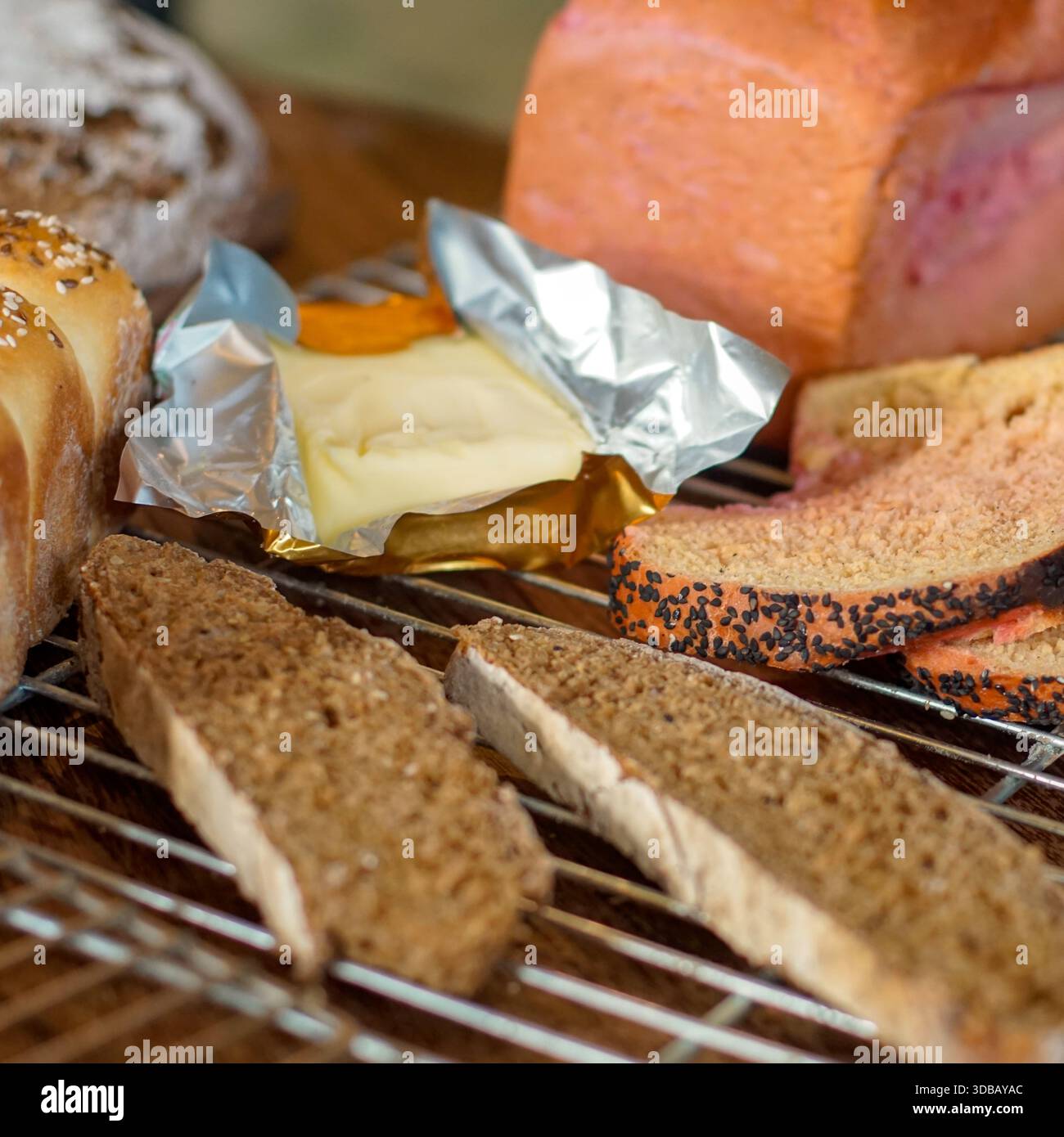 Assorted bread selection with butter on cooling rack, rustic bakery food background Stock Photo