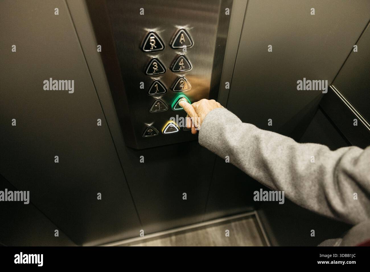 Senior hand choosing a floor by pressing a button inside a modern elevator Stock Photo