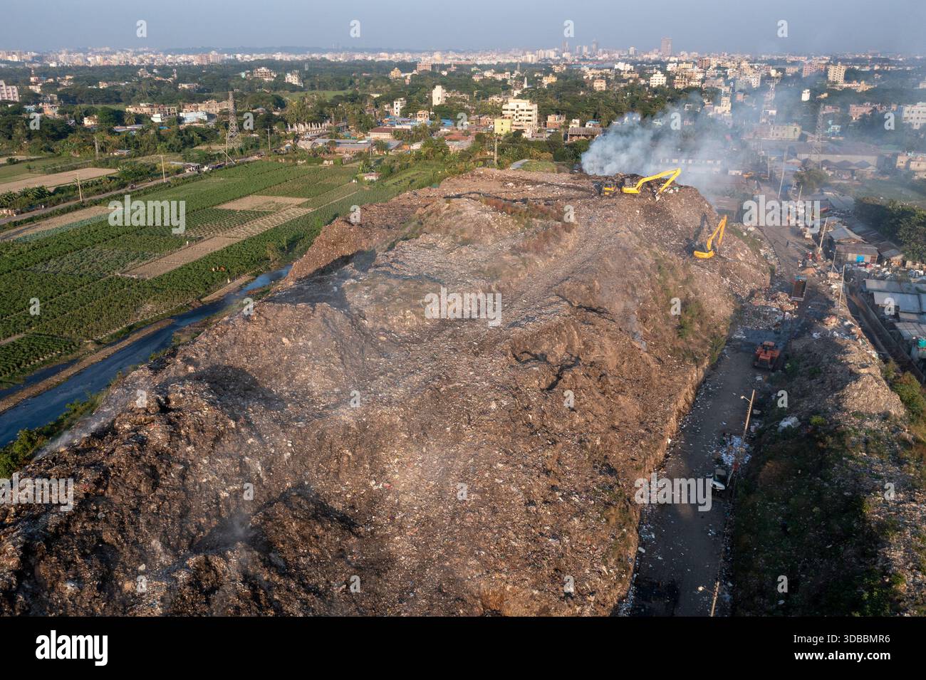 Aerial view of a sprawling landfill under a smoky sky, where ...