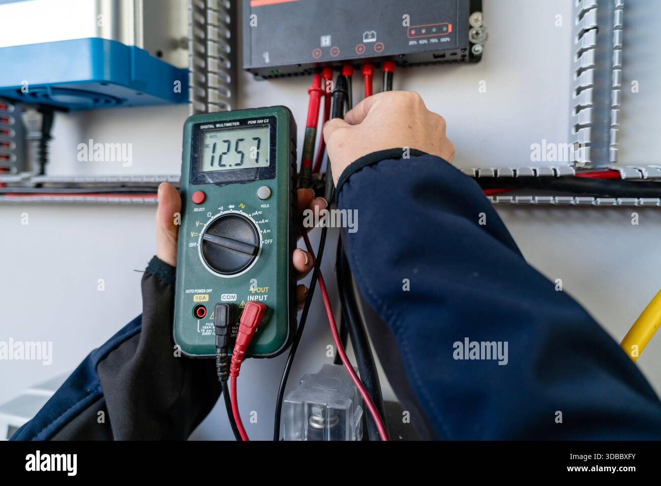 Hands using a digital multimeter to test voltage on a solar charge controller Stock Photo