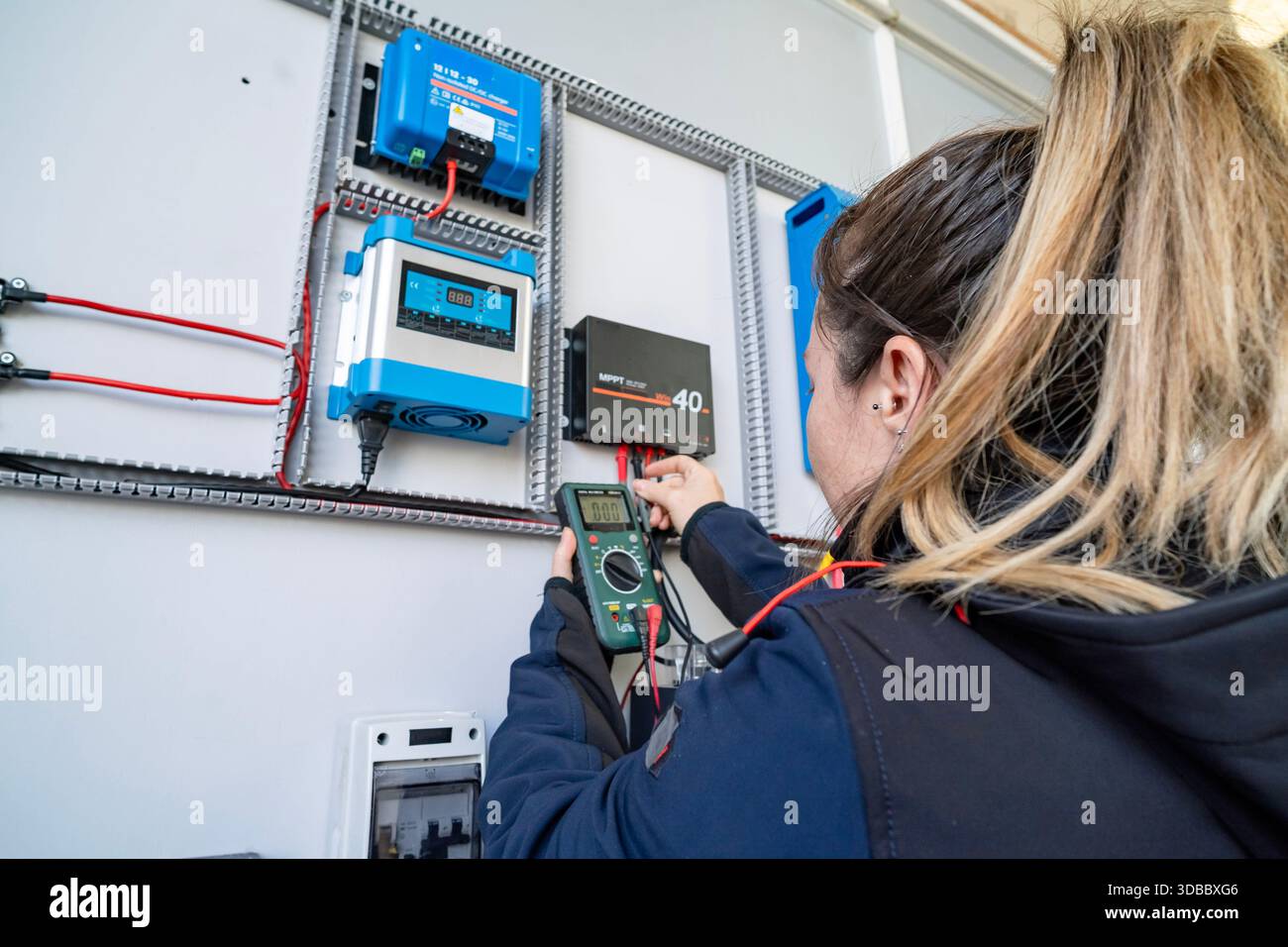 Technician using multimeter for testing electrical components on a solar power system Stock Photo