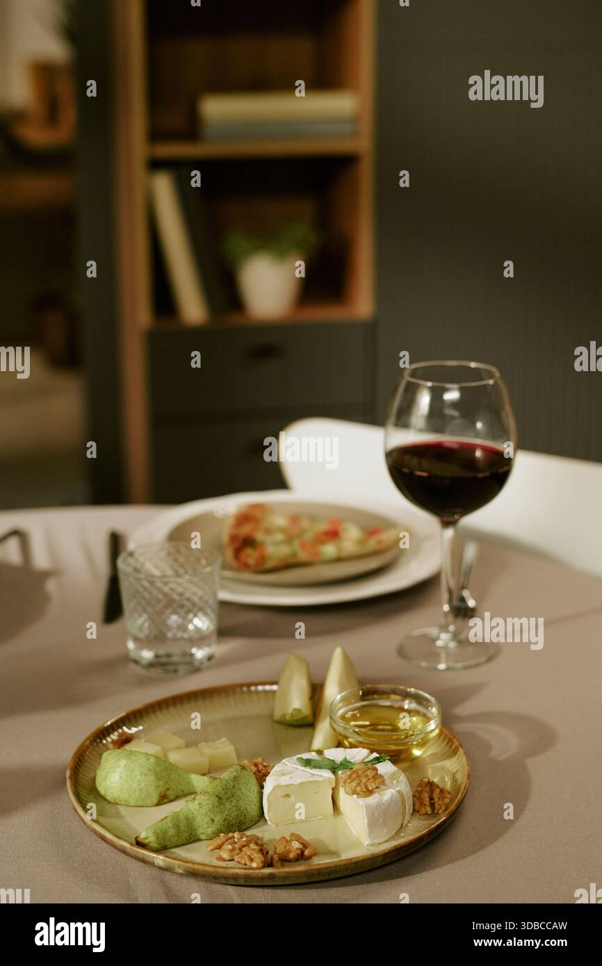 Cheese Platter with Walnuts and Pears Accompanying Glass of Red Wine Stock Photo