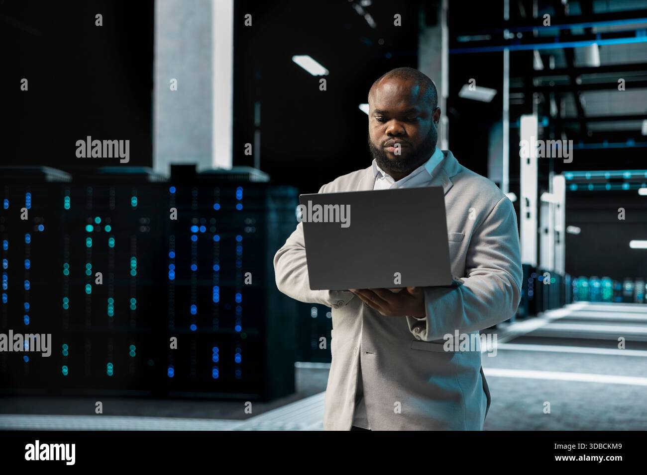 Data center computer scientist using laptop to protect servers from exploitable software vulnerabilities, auditing systems. Server farm employee looking for bugs slowing down rigs Stock Photo