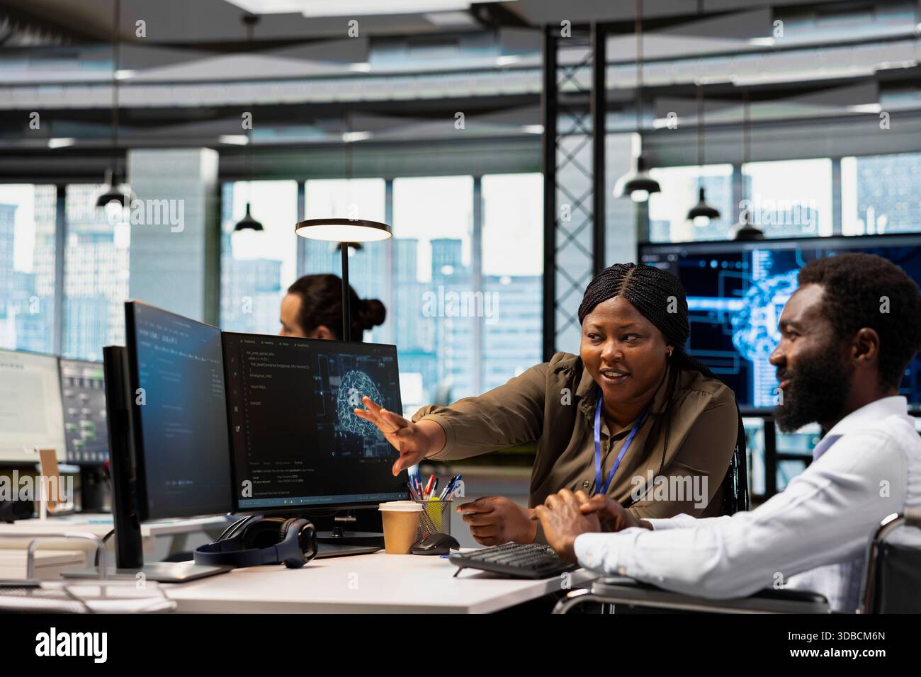 Happy team leader oversees developer in wheelchair using AI automation, refining algorithms. Joyous supervisor satisfied by progress done by programmer with paraplegia using artificial intelligence Stock Photo