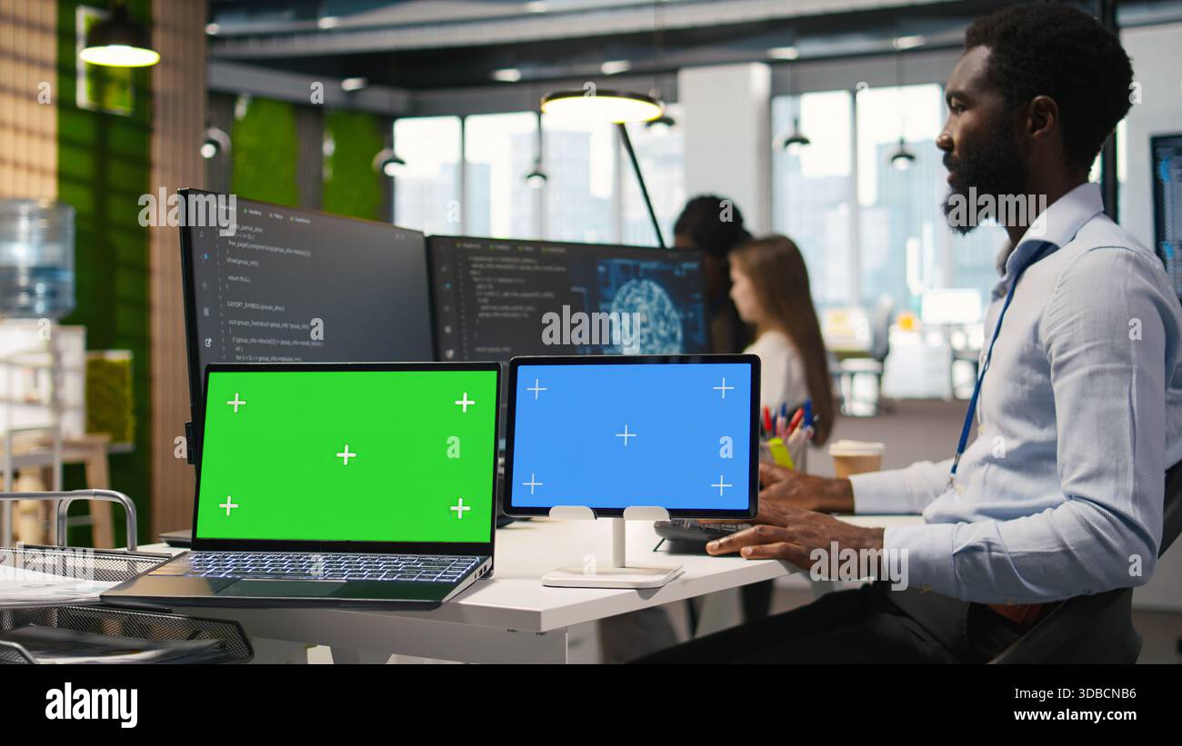 Software developer using AI on isolated screen laptop and tablet to optimize performance and forecast issues. IT expert in office training machine learning models using chroma key notebook, camera A Stock Photo