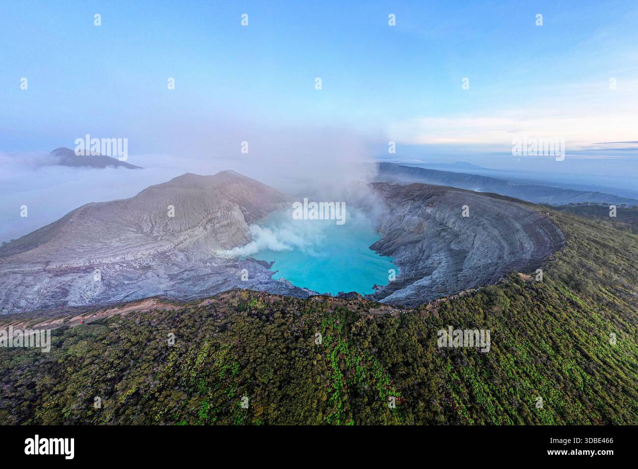 Spectacular Ijen volcano on Java island in Indonesia, aerial view of a volcano crater and blue volcanic lake with steaming vents at sunrise Stock Photo