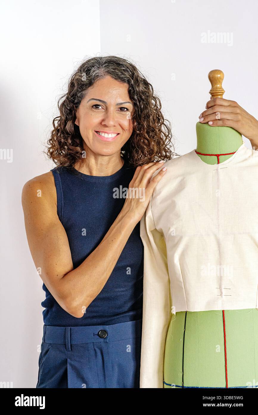 Female fashion designer posing with mannequin showing dress pattern ...