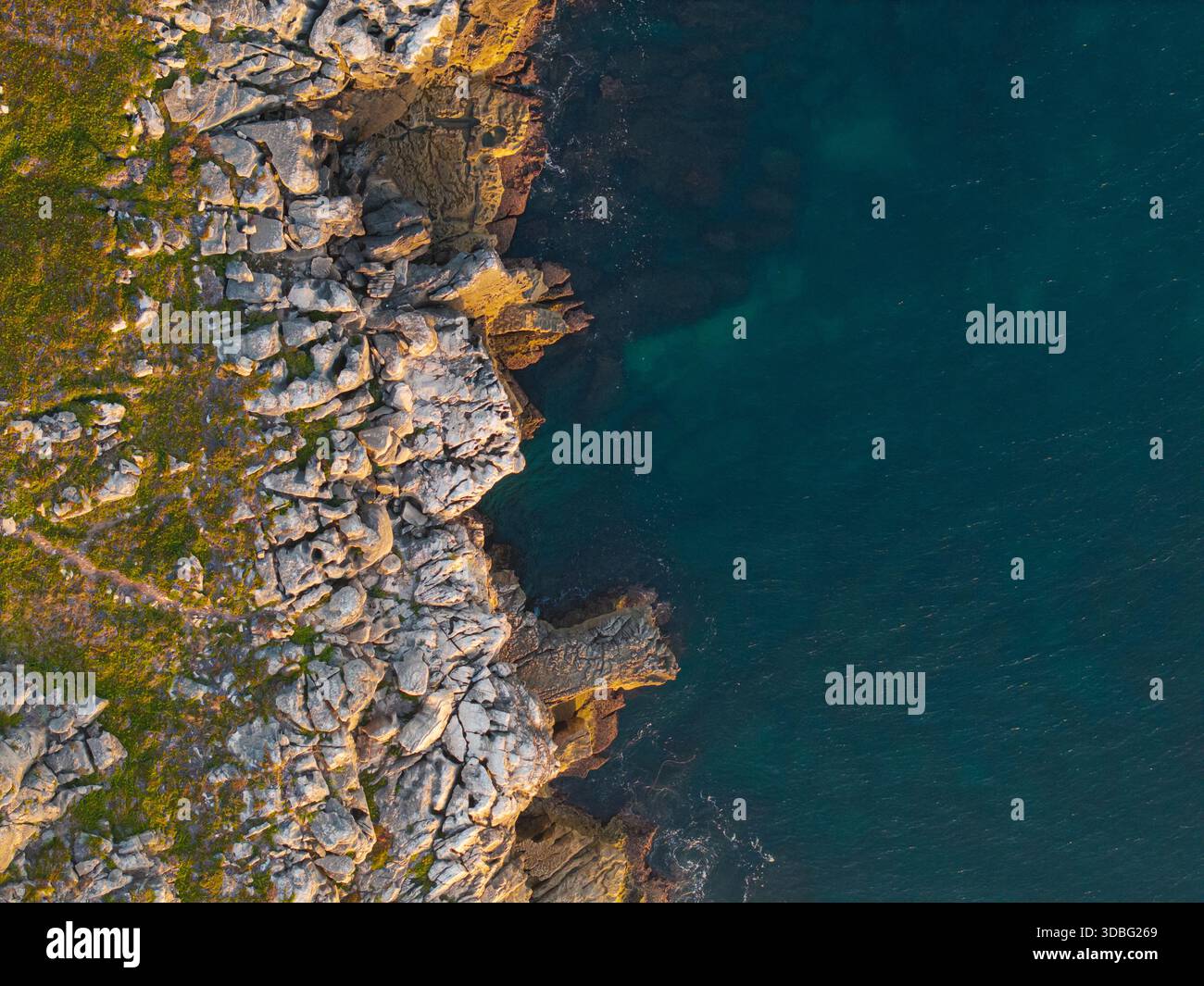 Vertical top-down aerial photograph showing a rugged cliff edge where ...