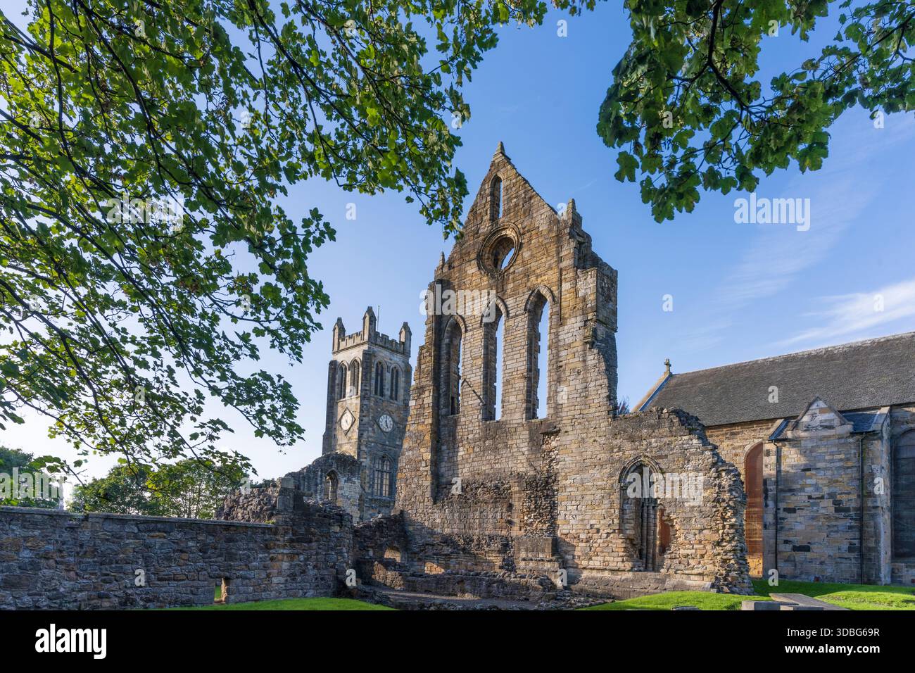 Stone Priory Ruined abbey and church with tall tower, stone walls, and bright blue ...
