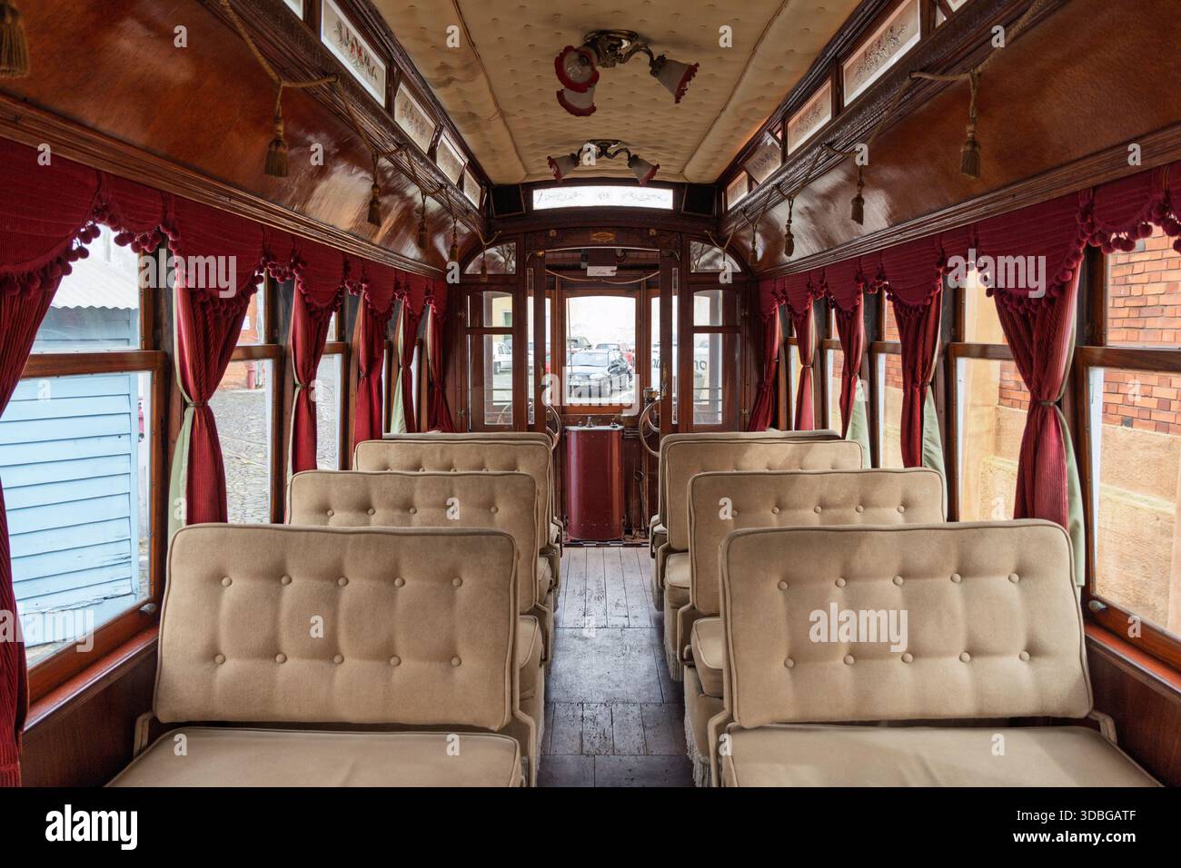 Interior view of a vintage red tram in Lisbon, featuring plush beige ...