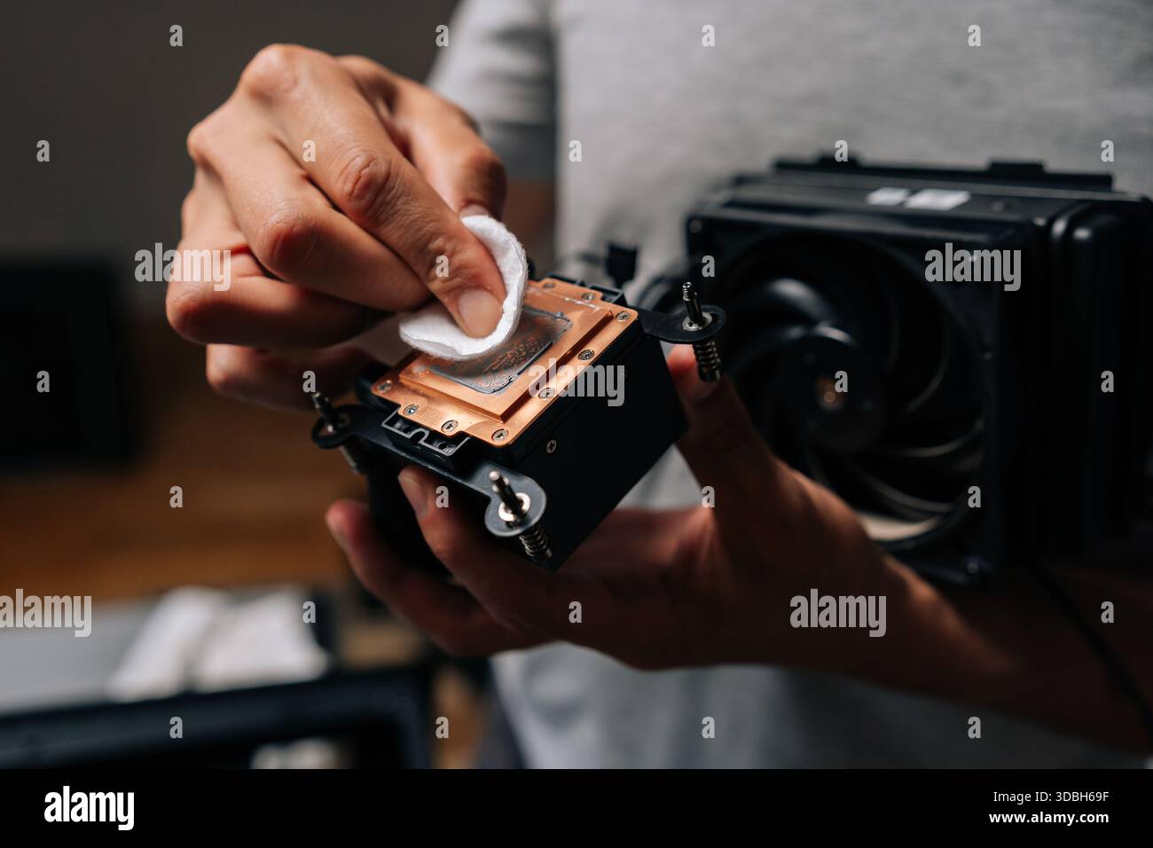 Computer technician cleaning processor cooling system with white cloth, ensuring optimal performance and preventing overheating during maintenance. Stock Photo