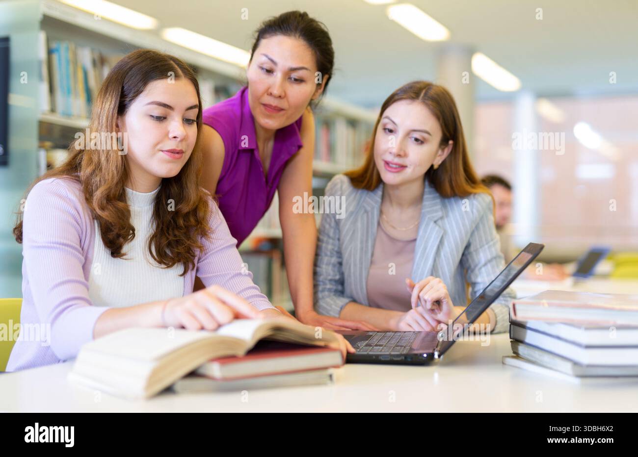 Three girls students, preparing for classes in the library Stock Photo ...