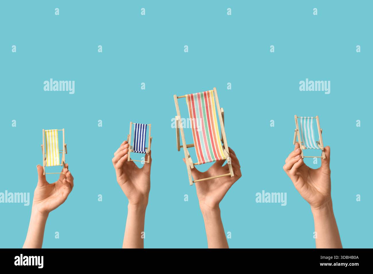 Female hands holding mini deck chairs on blue background Stock Photo