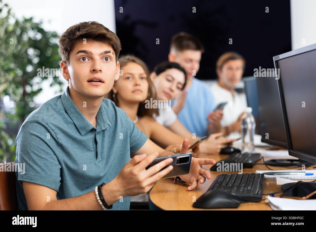 Excited young developer using mobile phone at IT startup presentation Stock Photo