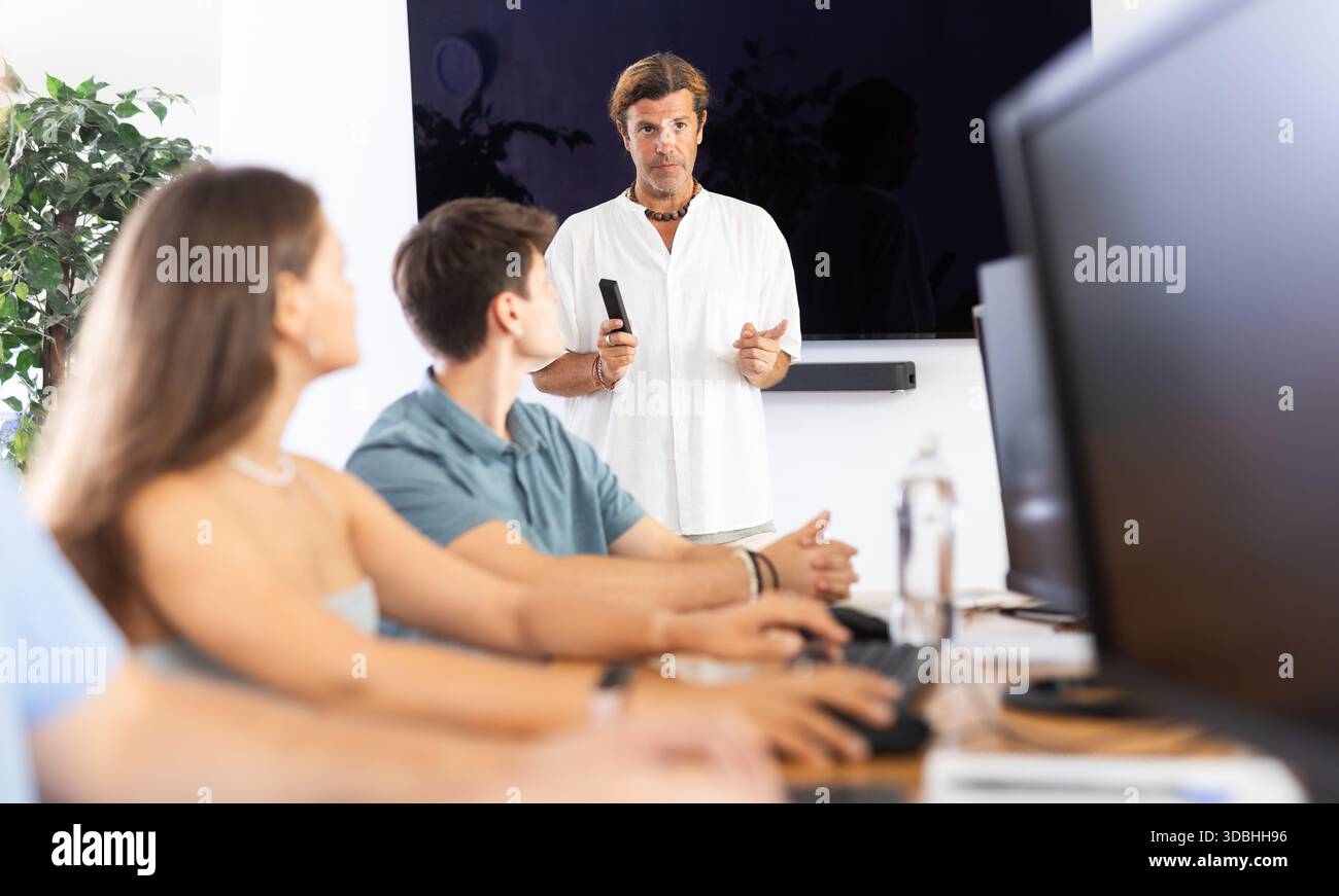 Experienced mentor explaining assigned tasks to young developers at IT startup Stock Photo