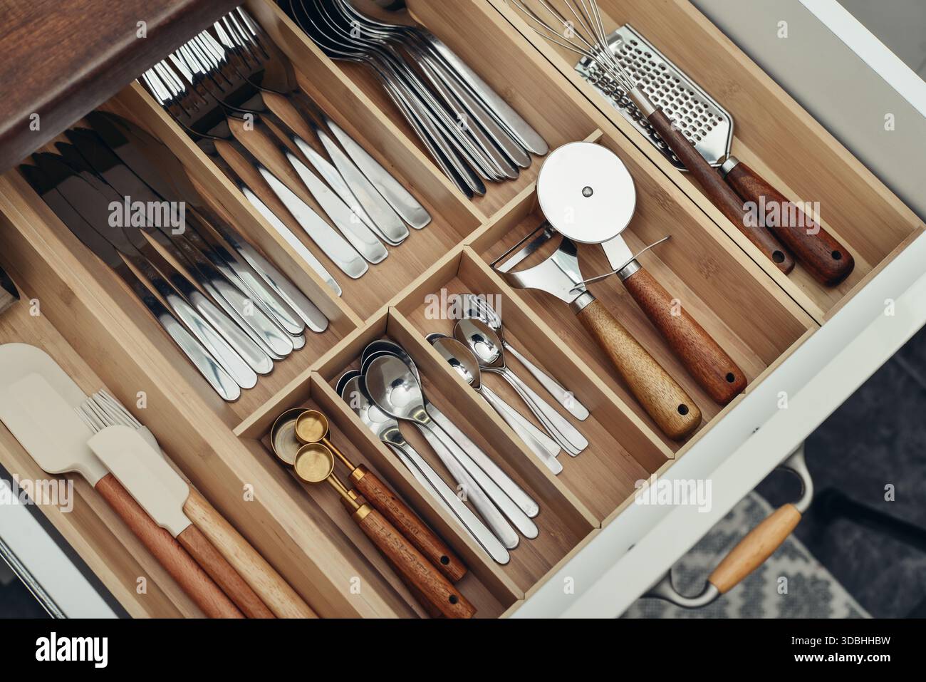 Bamboo organizer with cutlery in kitchen drawer, above view. Kitchen utensils storage. Stock Photo
