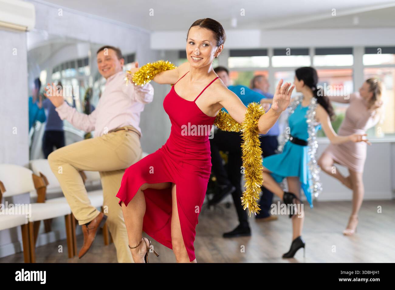 Happy brunette dancing jive with male partner during New Year party Stock Photo