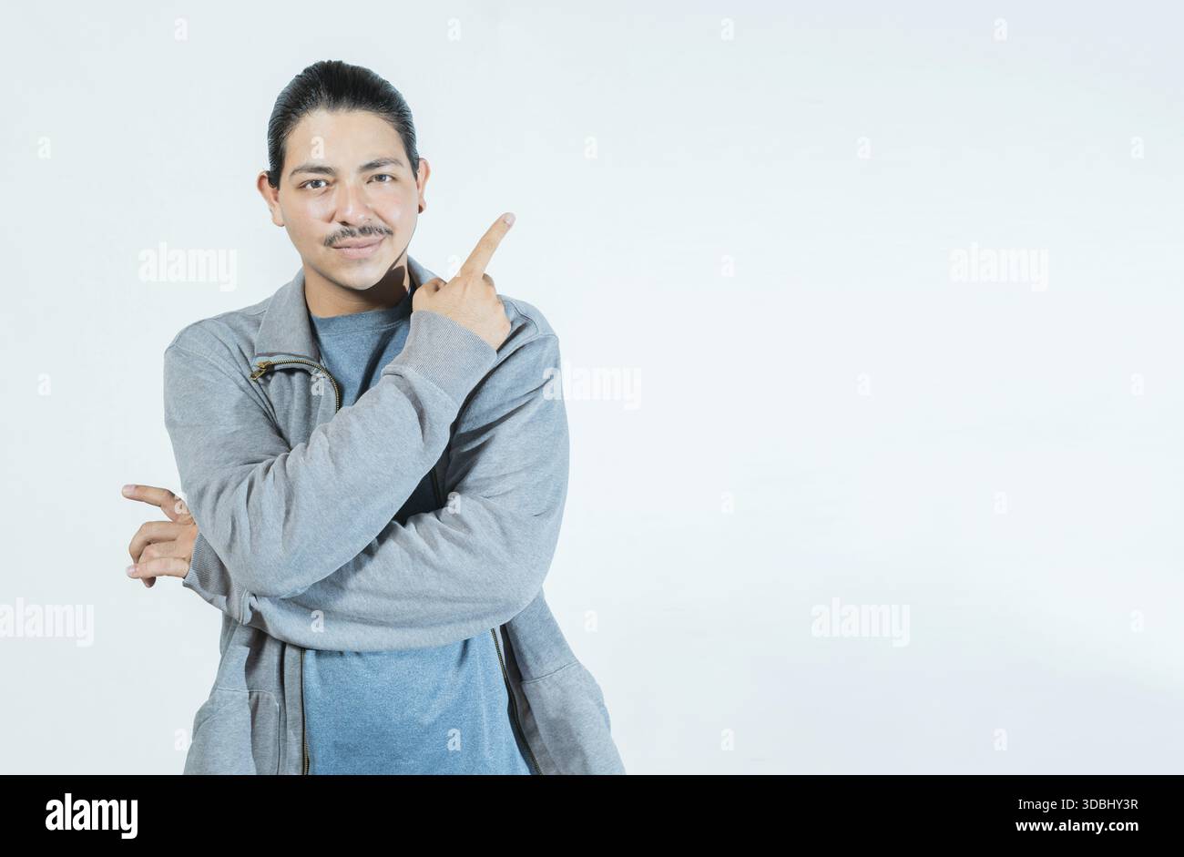 Latin guy pointing an advertising to side isolated. Smiling people pointing a banner on blank space Stock Photo